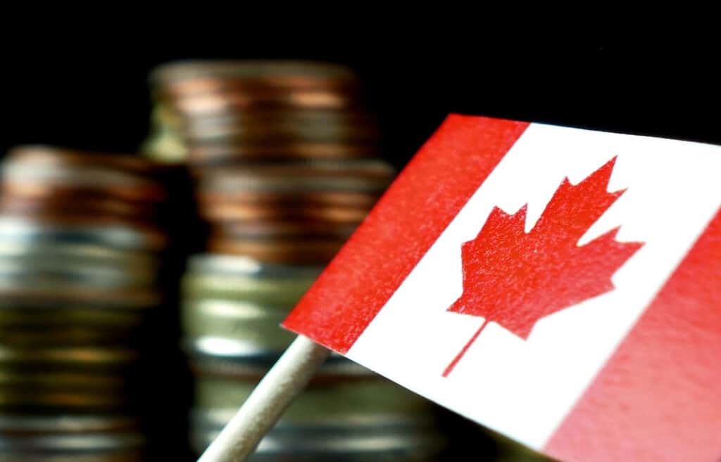 Canada flag waving with stack of money coins macro